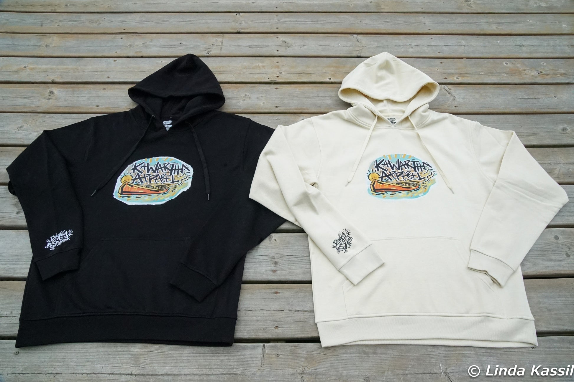 Kawartha Apparels Founders Edition Hoodie in Cottage White and black laid flat on a dock